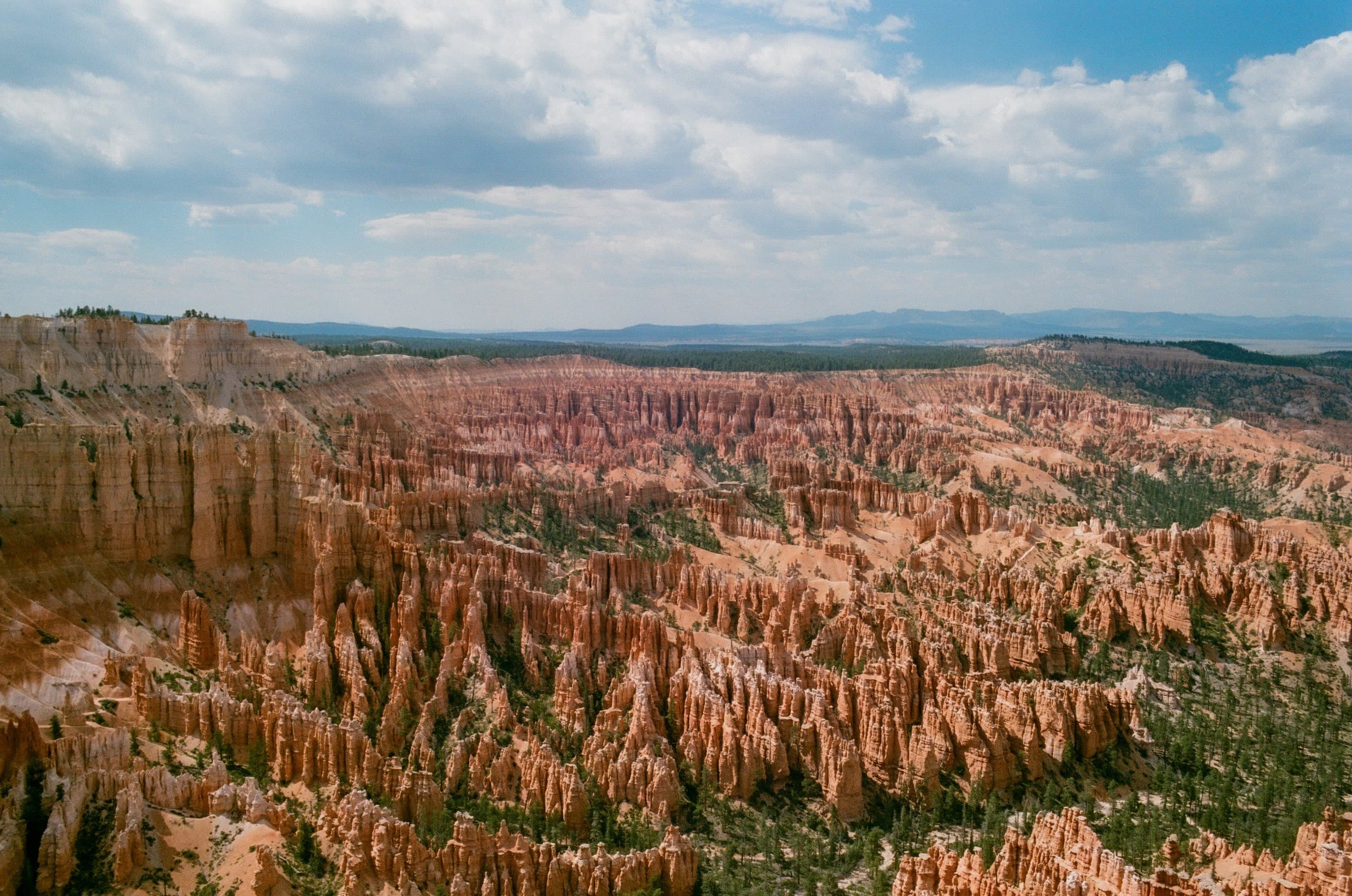 Red rock hoodoos filling a canyon under a wide sky of scattered clouds